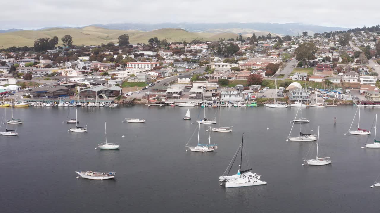 tomada aérea baja de la bahía de morro embarcadero con veleros en el puerto de morro bay, california