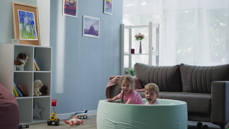 joyful kids laugh jumping into dry pool with colorful balls