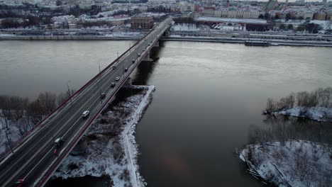 aerial tracking shot of vehicle crossing vistula river during snowy day in warsaw city,poland - tilt up