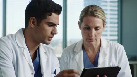 two diverse doctors discussing patient results on a digital tablet