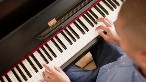 high angle view of biracial man playing piano at home, slow motion