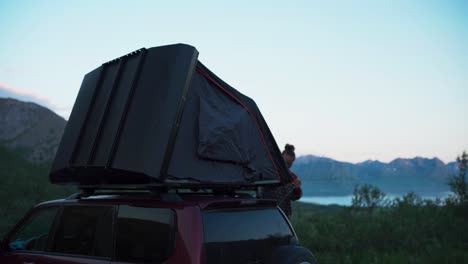 a man is setting car roof tent in nature background