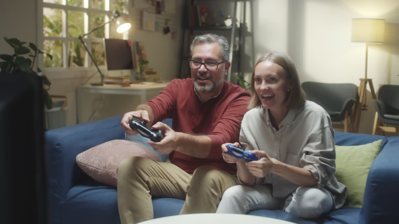 A happy couple playing video games together on a couch in their living room