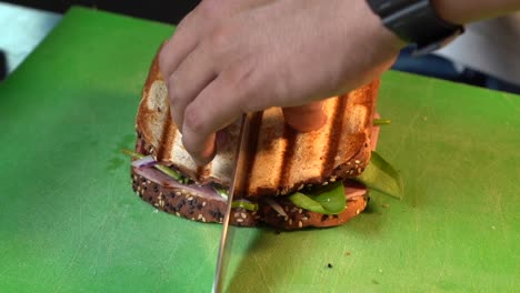 chef slicing cut half sandwich and showing ingredients