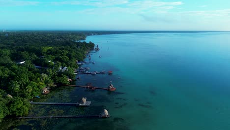 drone aerial landscape of wooden straw huts on hotel resort boardwalk jetty wharf in bacalar town village with clear lake cenote bay mexico vacation holidays rainforest