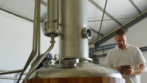 male worker using digital tablet while examining distillation tank 4k