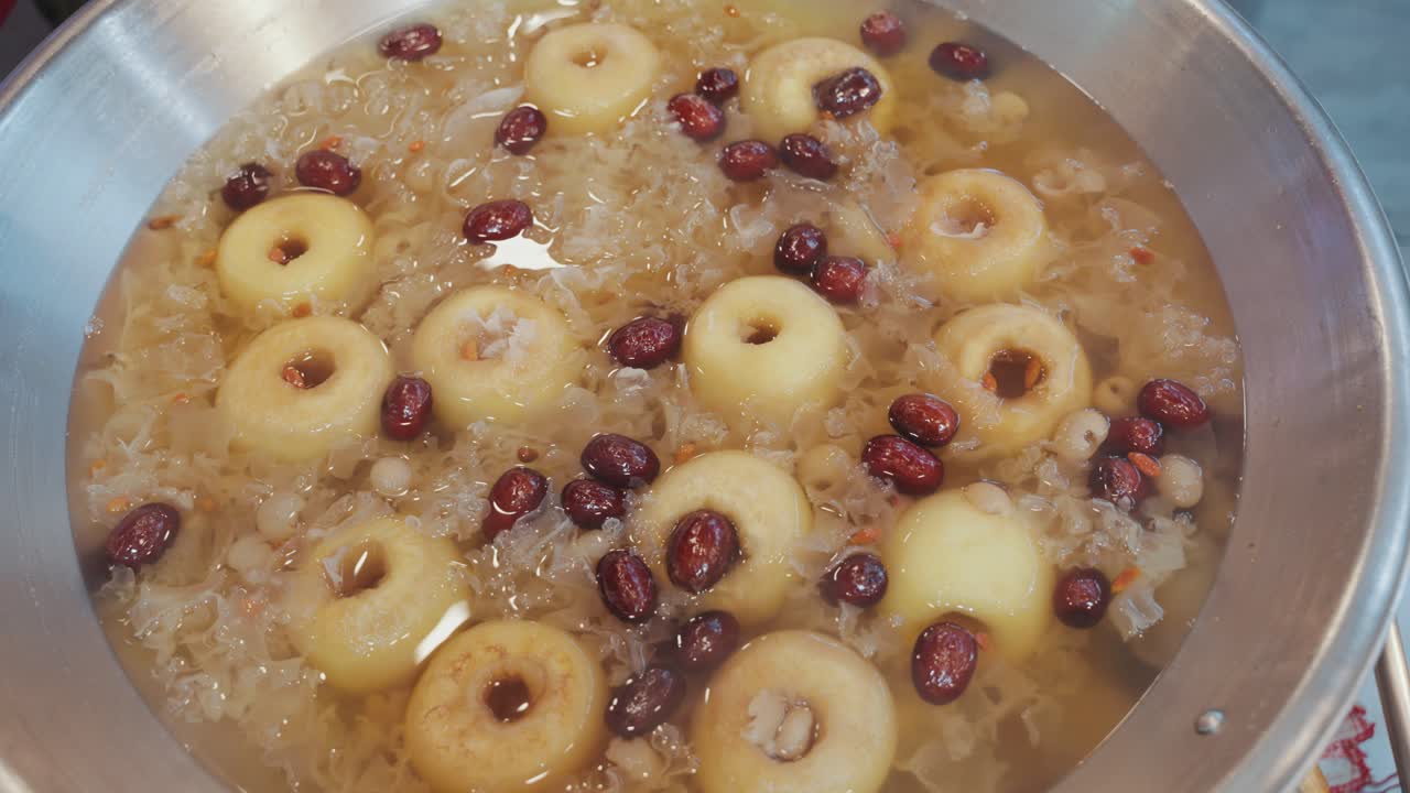 Close-up shot of a traditional Taiwanese sweet soup simmering in a pot, with whole pears, red dates, and snow fungus in a gently boiling, aromatic herbal broth.