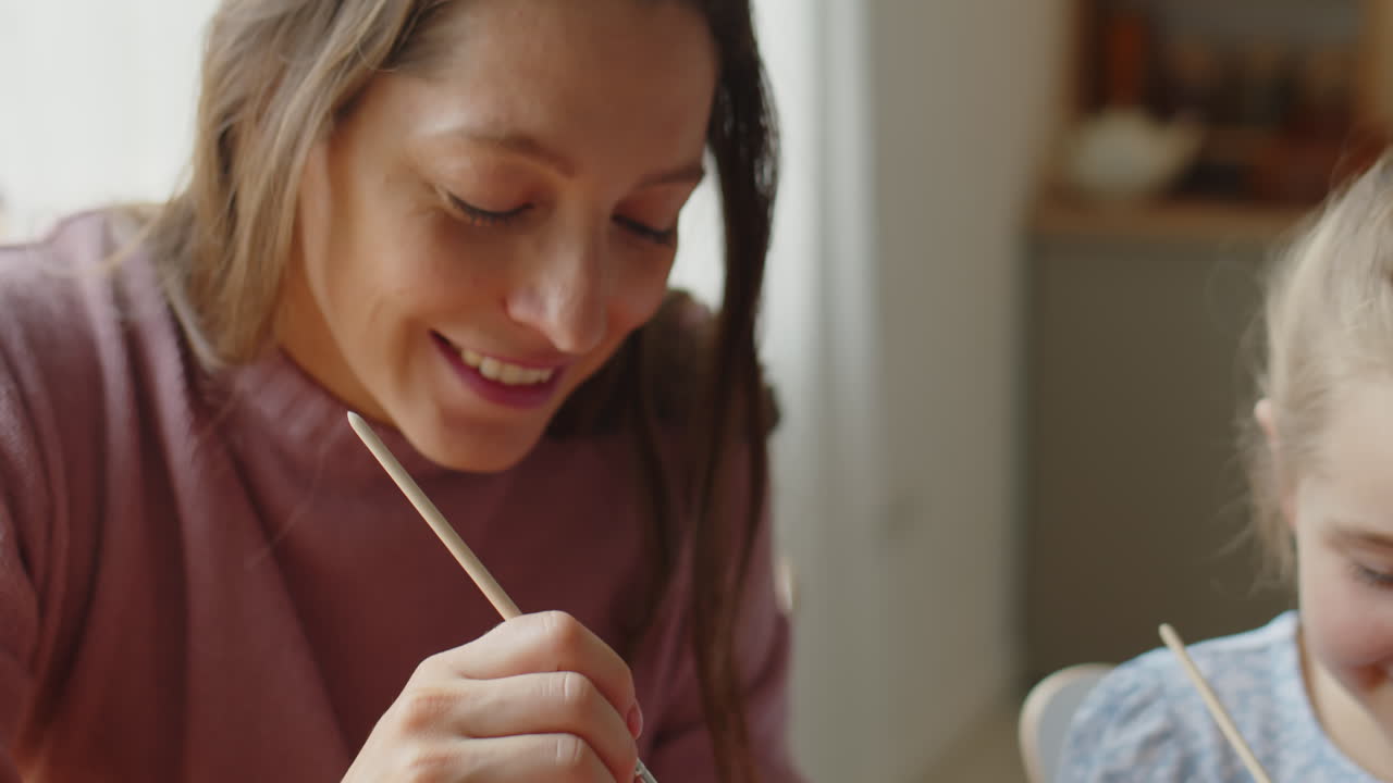 Mother and Daughter Painting Easter Eggs and Smiling