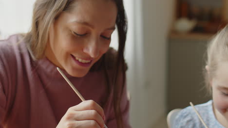 mother and daughter painting easter eggs and smiling