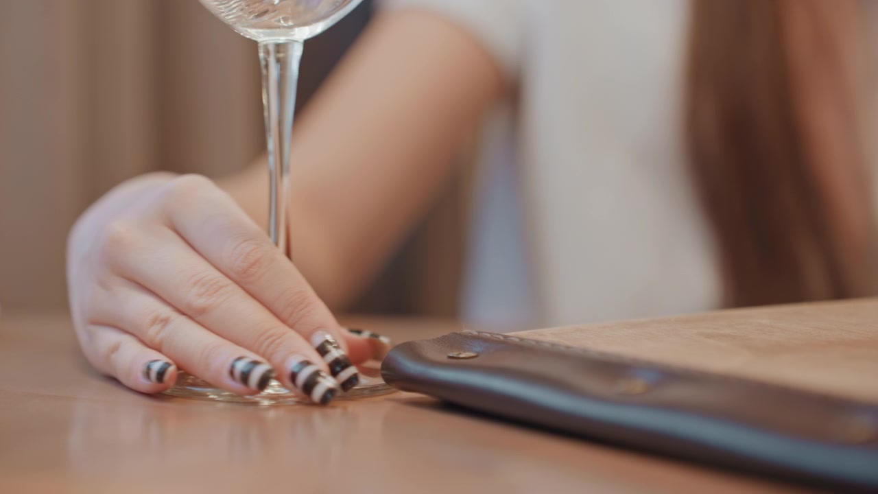 Donna elegante tocca delicatamente il bicchiere al caffè. Donna raffinata con unghie curate solleva silenziosamente il bicchiere di vino. Individuo sofisticato in un ambiente informale gesticola delicatamente con una mano ben curata