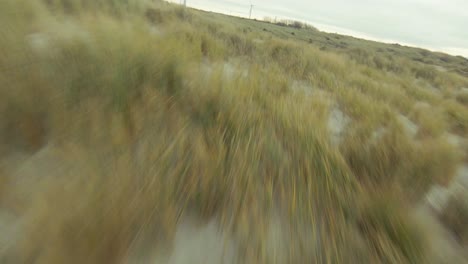 Drone-flying-low-over-the-dunes-at-a-Dutch-beach,-with-a-quick-turn-in-the-end