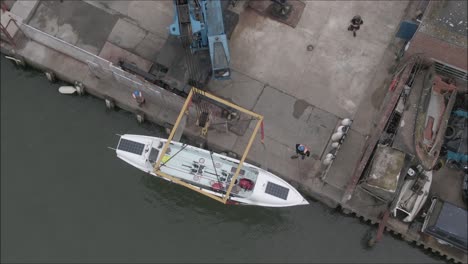 crane loading rowing boat into the sea