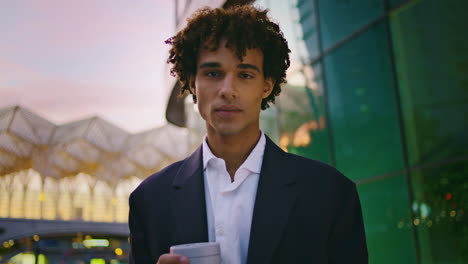 happy man looking camera business district closeup. businessman holding coffee