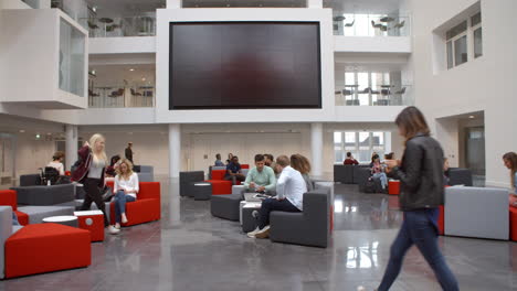 los estudiantes van y vienen en el concurrido vestíbulo de una universidad.