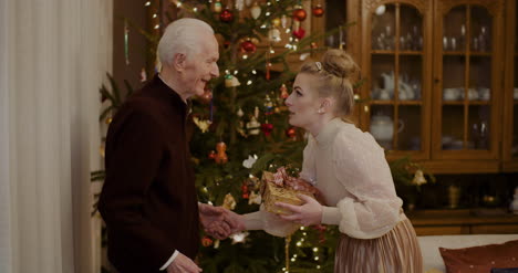 Woman-Giving-Christmas-Present-To-Grandfather-At-Home-3