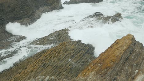 Waves-crashing-over-coastal-bluffs-on-pacific-ocean-on-overcast-day