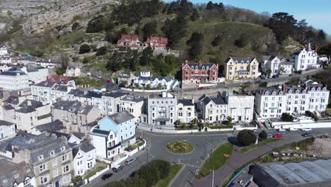 Colourful-Llandudno-seaside-holiday-town-hotels-against-Great-Orme-mountain-aerial-view-push-in-orbit-left