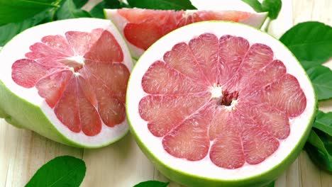 top view rotate red pomelo fruit with leaves on wooden table in garden, red pomelo fruit with leaves in wooden background 4k resolution.