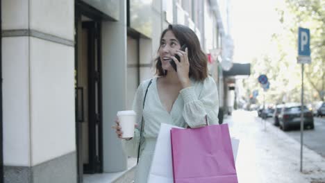 Latin-lady-talking-on-smartphone-and-looking-at-shop-windows