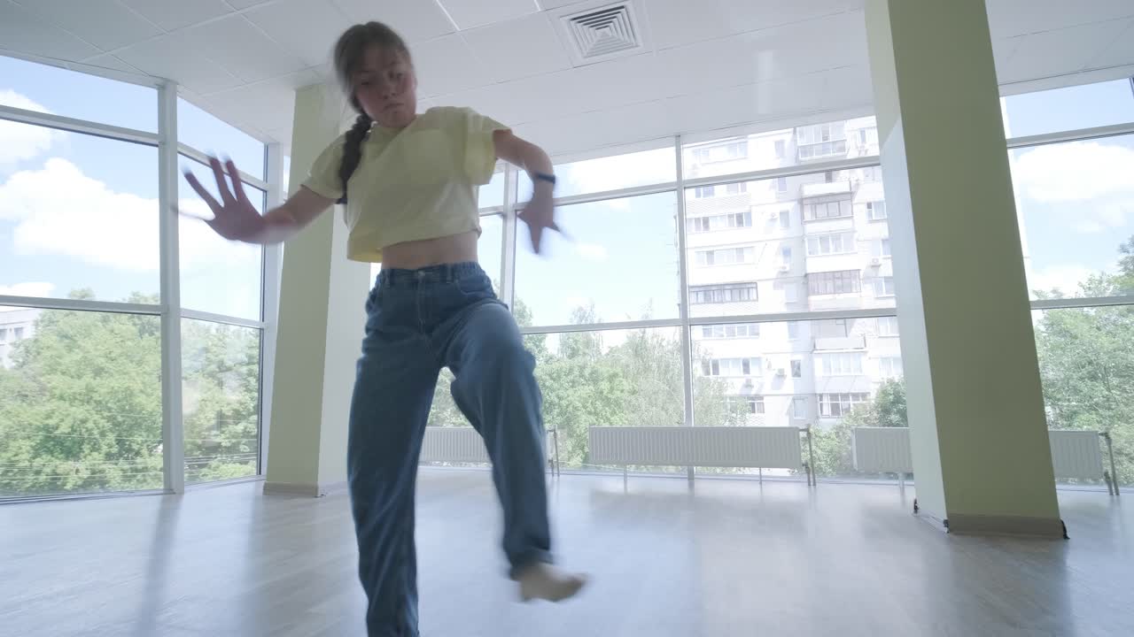 스타일리시한 젊은 소녀가 브레이크 댄스와 안무로 춤을 춘다.