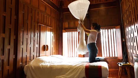 person installing mosquito net over bed