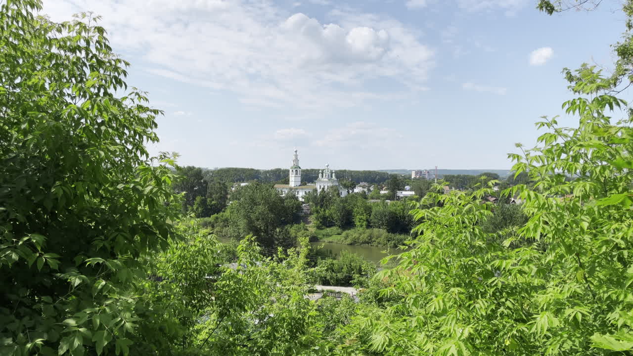 나무 로 둘러싸인 교회 와 강 이 있는 도시 의 파노라마 뷰