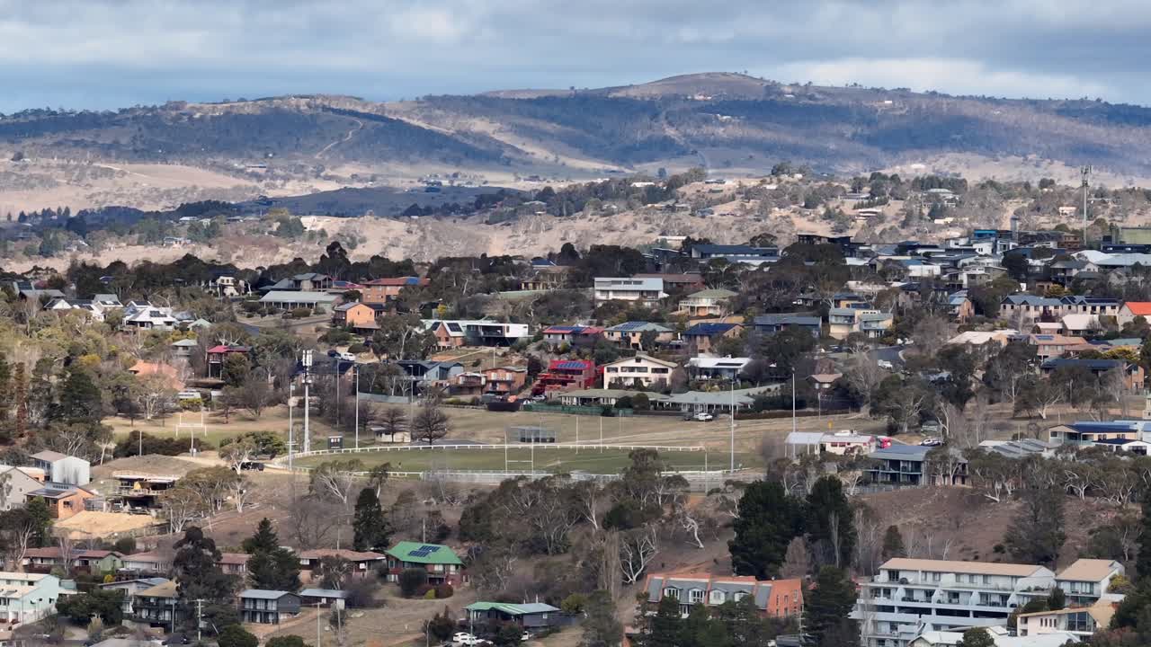 Aerial: drone shot sliding past houses on the hills around Jindabyne town, Australia
