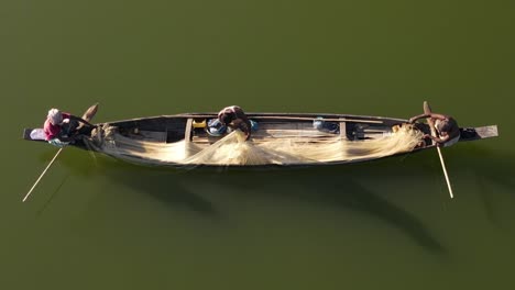 aerial shot of a small wooden boat with fishermen catching fish using net in traditional style in surma river, bangladesh