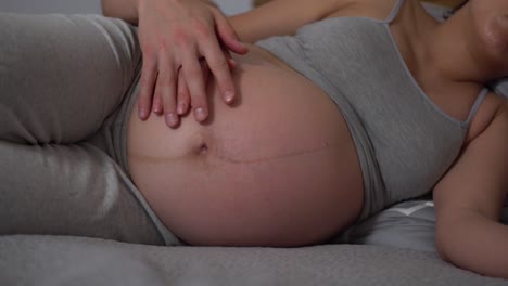 Beautiful-pregnant-woman-and-her-handsome-husband-hugging-the-tummy-while-laying-on-the-bad