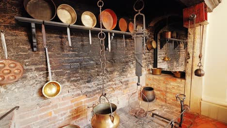 restored palace kitchen features copper cookware above blackened brick fire