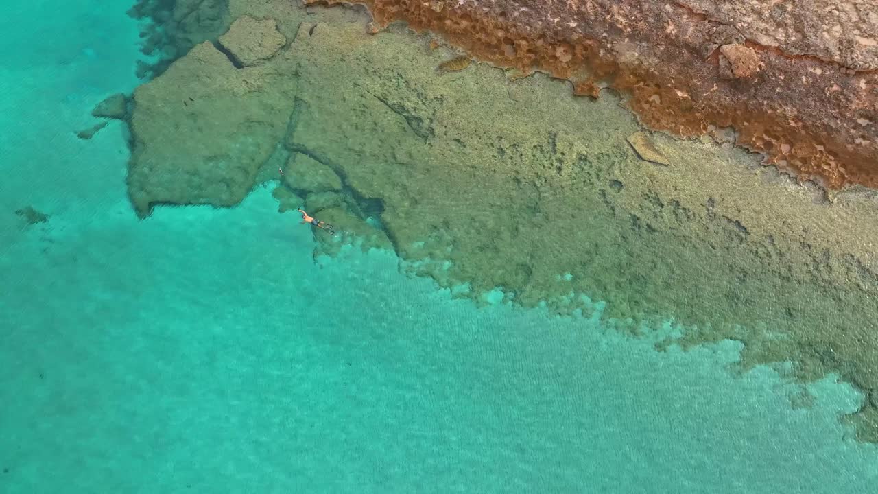 여름날 스페인의 바위가 많은 해안선을 따라 스노클링하는 사람