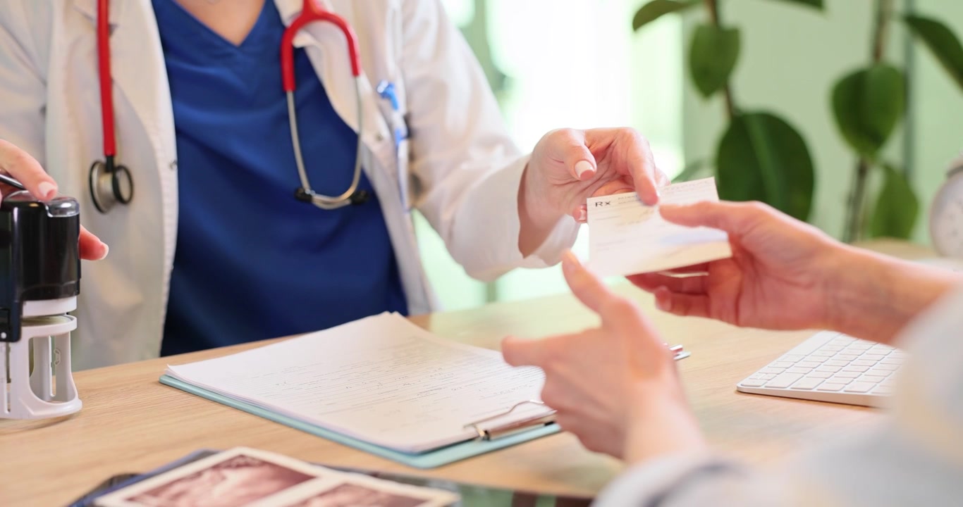 Doctor applies stamp onto patient medical prescription in clinic