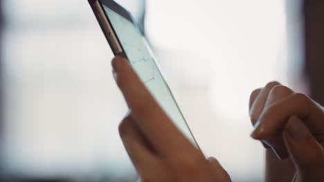 close up of womans hands using smart phone to read business graphs