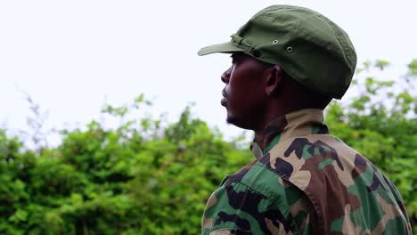 african soldier standing still waiting for order in forest, overcast day