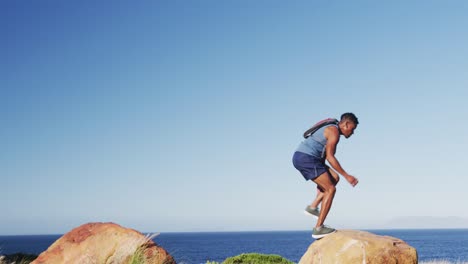 african american man exercising outdoors jumping on rocks in countryside on a mountain