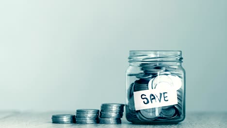 a  money coins falling into  glass jar with label of save text , business and financial of  money saving concept , 4k dci resolution