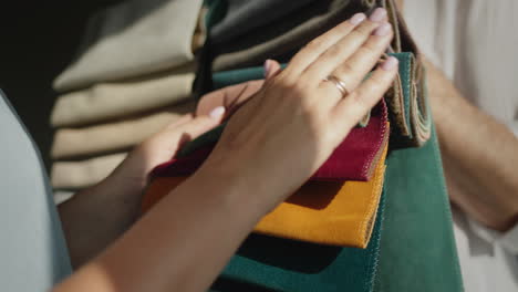 the buyer chooses the fabric in the textile store, the seller holds samples with multi-colored fabric