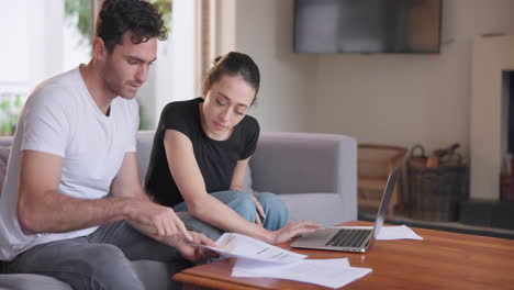 pareja, documentos y computadora portátil en el sofá para el presupuesto