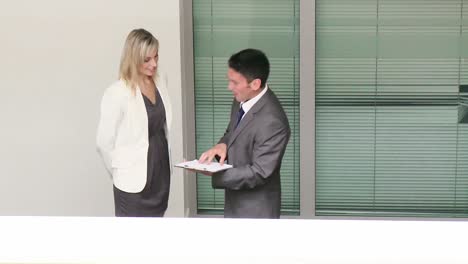 businessman and businesswoman speaking in corridor