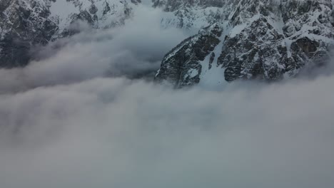 Flight-above-rolling-cotton-clouds-with-Alps-mountains-snowy-white-peaks