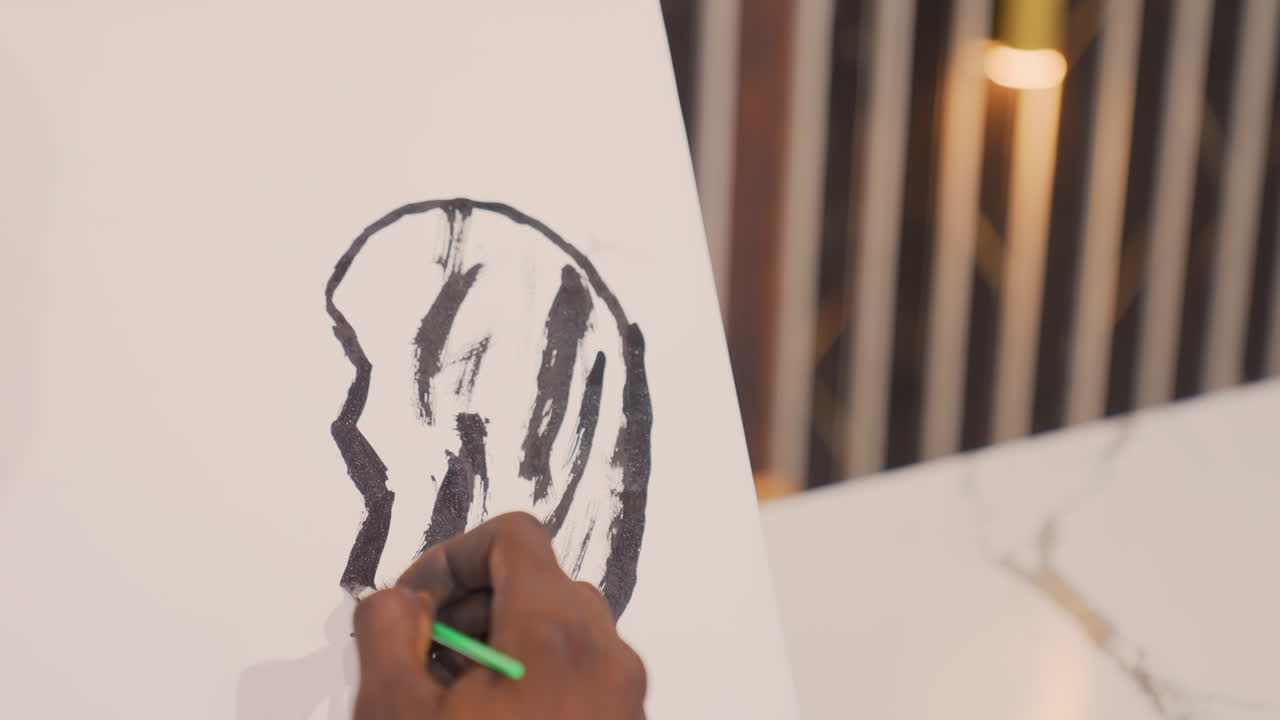 Black painting on upright canvas closeup of hand adding textured strokes with green pencil, warm lamp glow over marble tabletop, modern illustrator iterating silhouette lines and shading