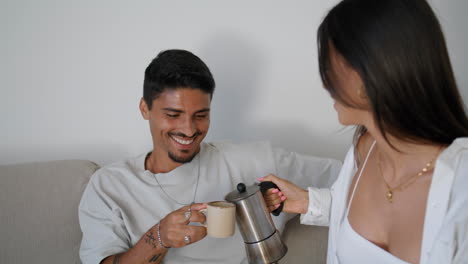 smiling couple drinking coffee at sofa together closeup. newlyweds taking break