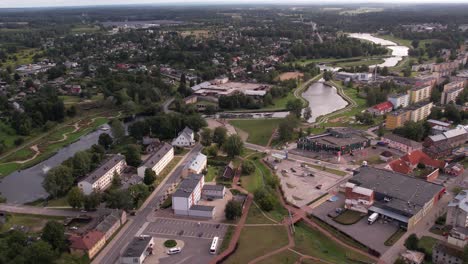 a drone captures an aerial view of the small town of valka, showcasing its buildings, streets, and surrounding greenery. the peaceful townscape contrasts with the natural beauty of the area.