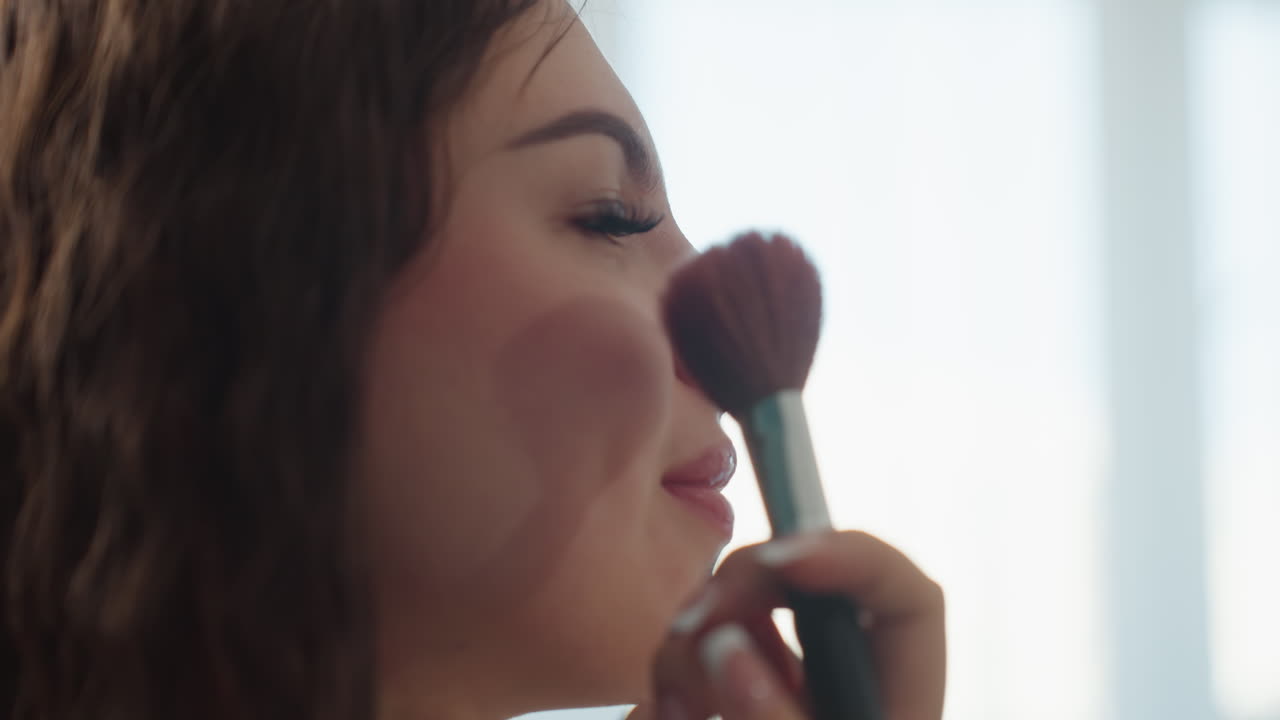 Caucasian Model Closing Eyes While Brush Applies Blush To Cheek, Soft Backlight From Window, Gentle Smile, Slow Calming Motion, Professional Brush And Powder Visible, Relaxed Beauty Routine