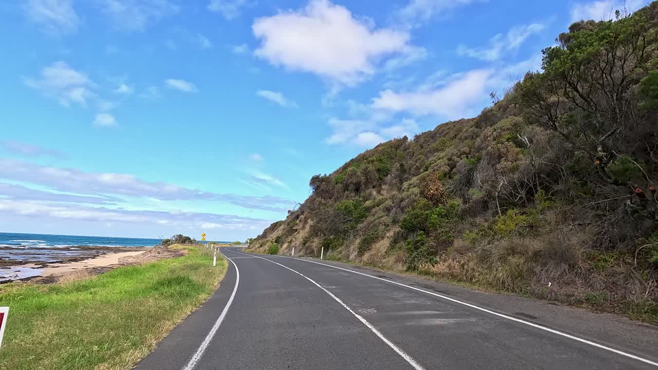 A picturesque drive along the Great Ocean Road, showcasing coastal views and lush landscapes under clear blue skies