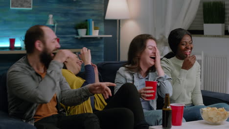 Multiracial-team-watching-comedy-movie-series-while-sitting-on-sofa