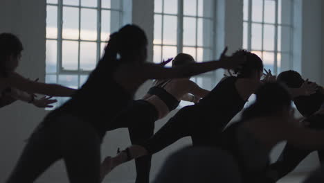 yoga class group of multiracial women practicing warrior pose enjoying healthy lifestyle exercising in fitness studio at sunrise