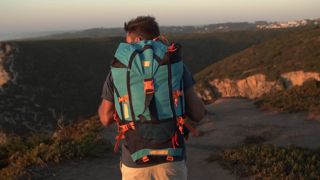 mochilero masculino activo caminando por un sendero en las montañas