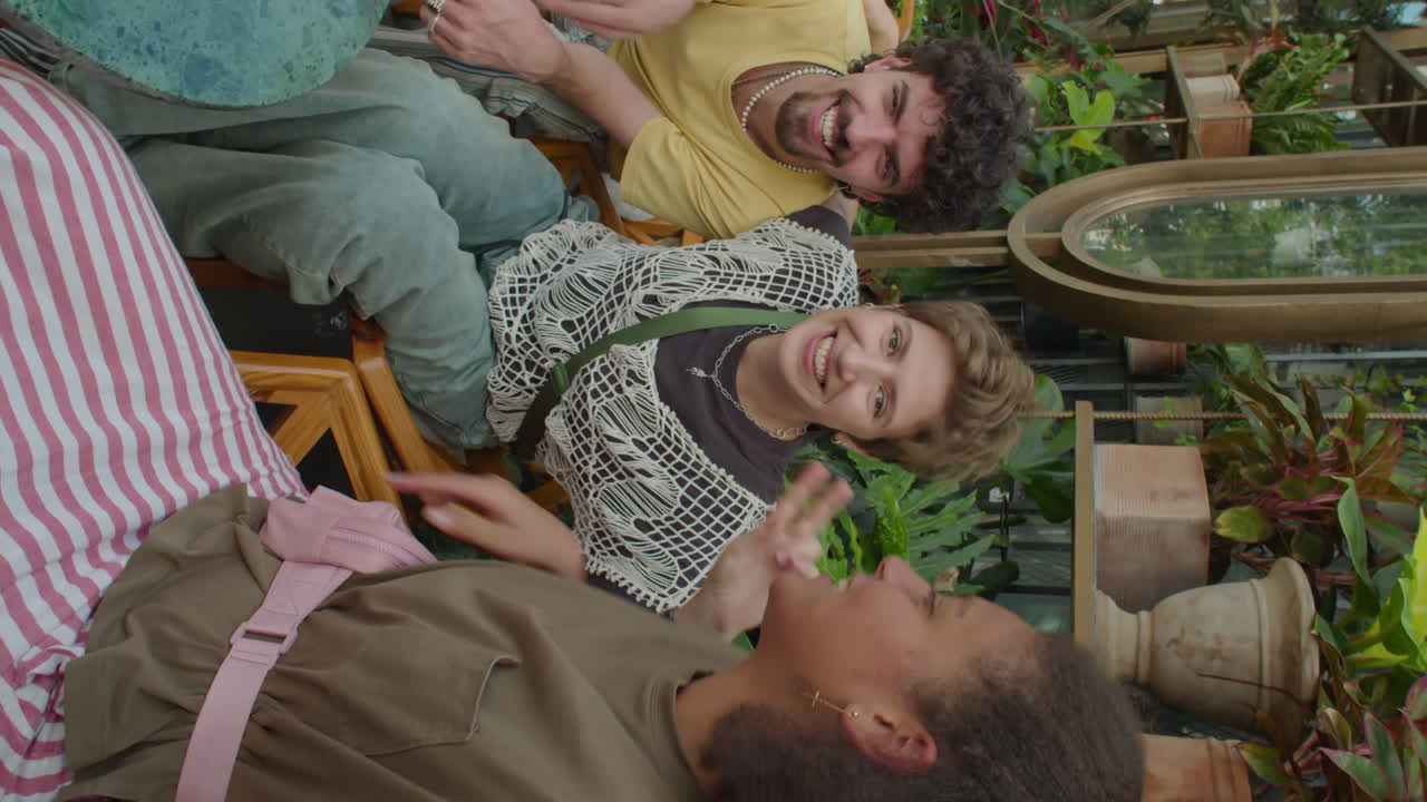 Smiling Friends Waving and Chatting on Camera in Outdoor Cafe