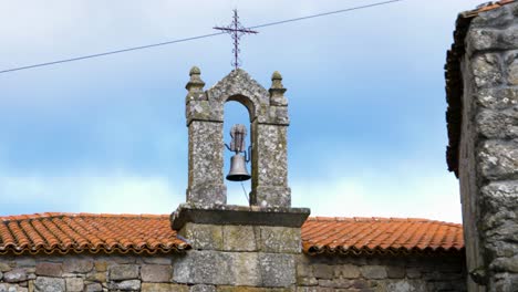 vista de amplio ángulo de la campana de hierro que descansa entre el arco de pilares de piedra en la iglesia de techo naranja